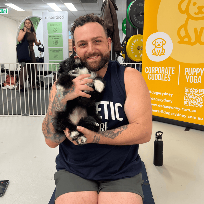 A man holding a fluffy black and white puppy against his chest