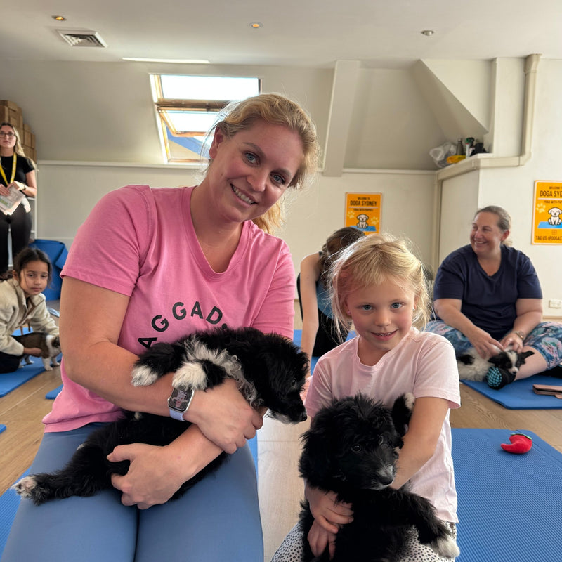 A woman and a girl holding two fluffy black and white puppies